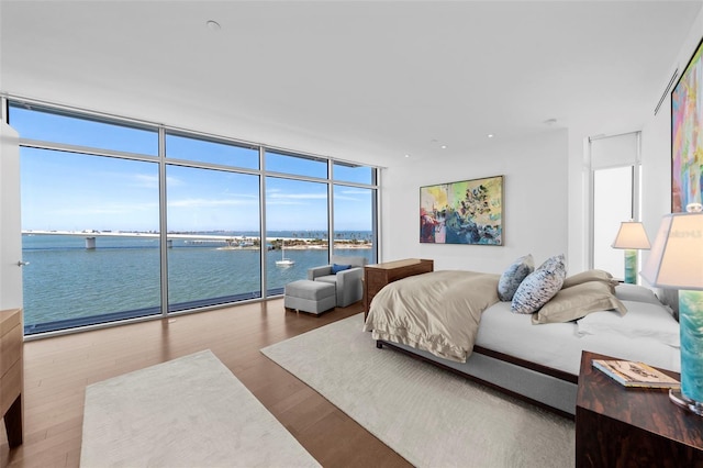 bedroom with multiple windows, a water view, and wood-type flooring