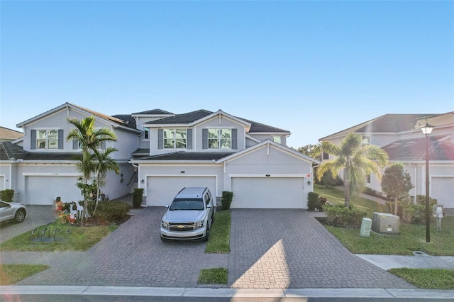 view of front of house with decorative driveway, an attached garage, and stucco siding