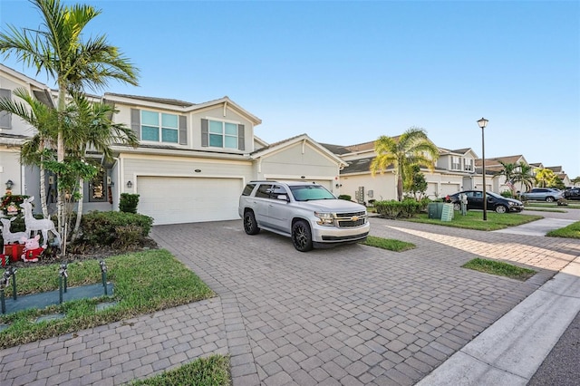 view of property with a residential view, decorative driveway, and an attached garage