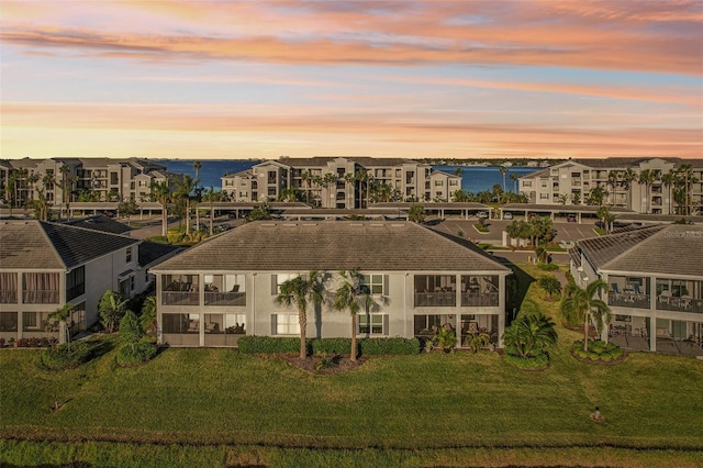 aerial view at dusk featuring a residential view and a water view