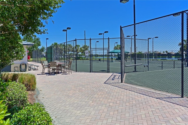 view of property's community with a tennis court, a gate, and fence