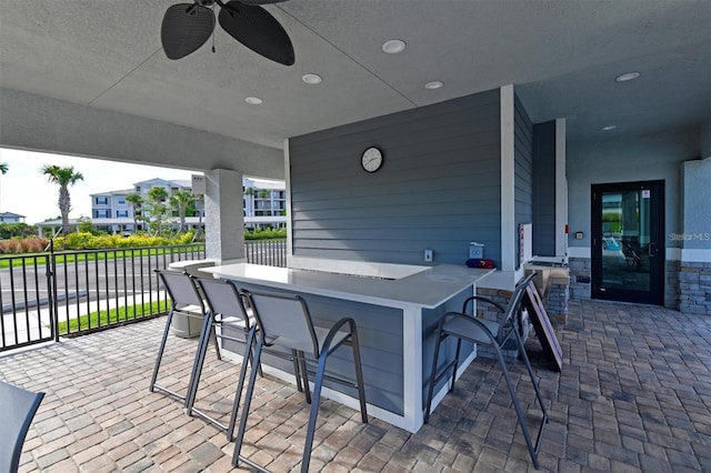 view of patio with a ceiling fan, fence, and outdoor dry bar