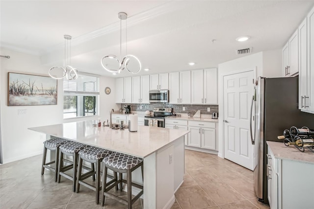 kitchen featuring a breakfast bar area, visible vents, white cabinetry, appliances with stainless steel finishes, and backsplash