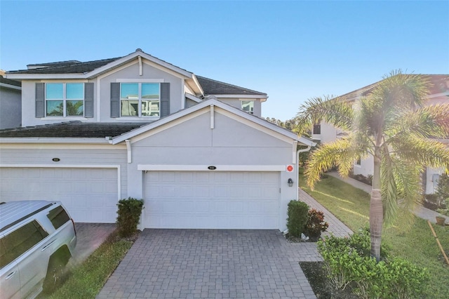 view of front facade with decorative driveway, an attached garage, and stucco siding