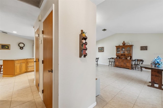 hallway with light tile patterned floors and lofted ceiling