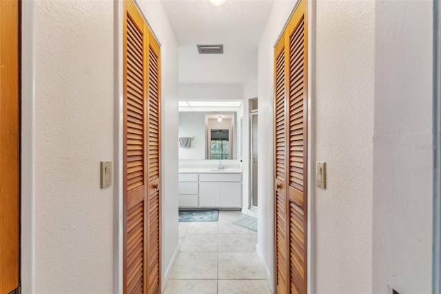 corridor featuring sink and light tile patterned floors