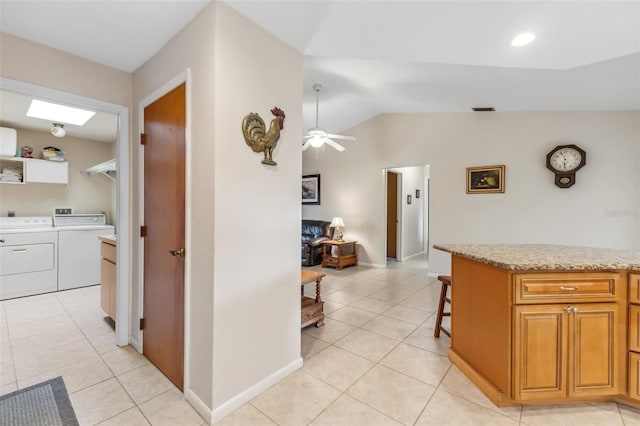 hall featuring light tile patterned floors, lofted ceiling, and independent washer and dryer