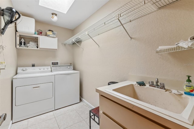 clothes washing area with washing machine and dryer, a skylight, light tile patterned floors, and sink