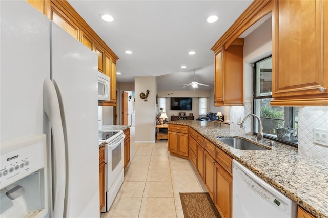 kitchen featuring white appliances, light tile patterned floors, decorative backsplash, sink, and light stone counters