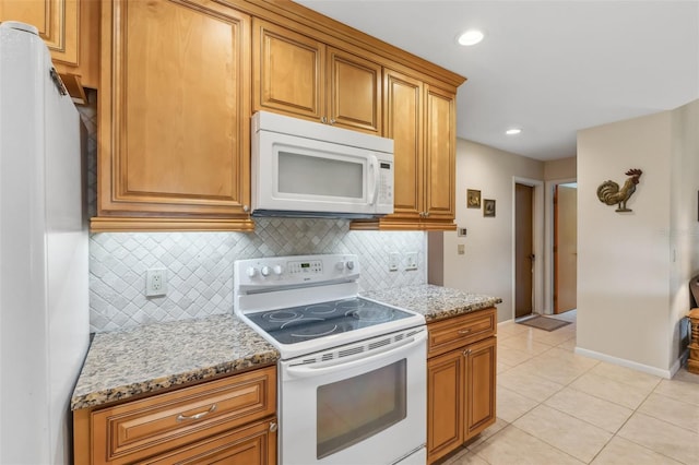 kitchen with light stone countertops, white appliances, light tile patterned floors, and tasteful backsplash