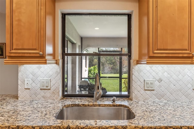 kitchen with sink, tasteful backsplash, and light stone counters