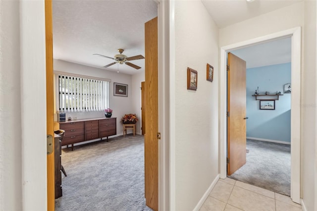 corridor featuring a textured ceiling and light colored carpet