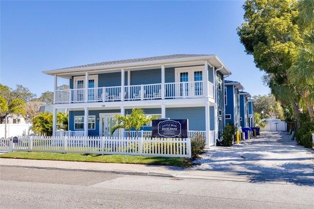 719 Douglas Ave, Dunedin, FL 34698 - view of front of property with a balcony, a fenced front yard, driveway, and covered porch