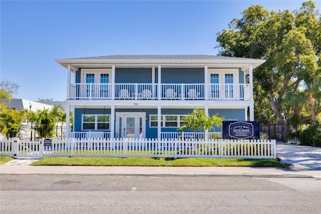 719 Douglas Ave, Dunedin, FL 34698 - view of front facade featuring a balcony, covered porch, a fenced front yard, and concrete driveway