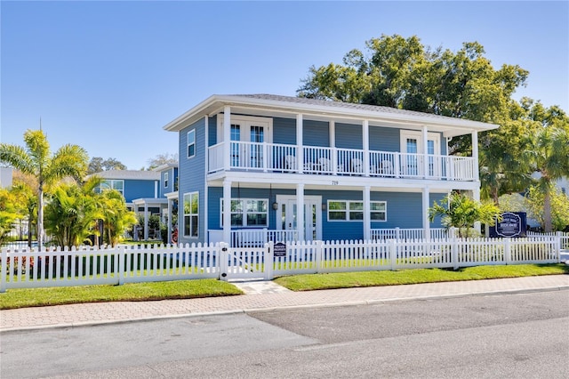719 Douglas Ave, Dunedin, FL 34698 - view of front of house featuring a balcony, a porch, a fenced front yard, and a gate