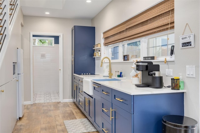 kitchen with sink, light hardwood / wood-style flooring, and blue cabinets