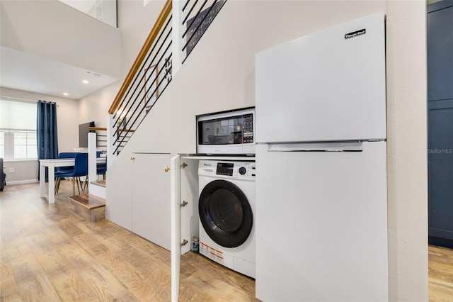 clothes washing area with light wood-type flooring and washer / clothes dryer