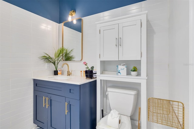 bathroom with vanity, toilet, and tile walls