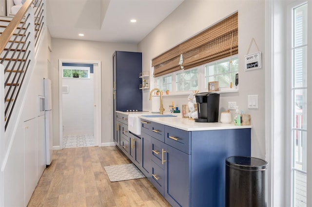 kitchen with blue cabinetry, a wealth of natural light, sink, and light hardwood / wood-style floors