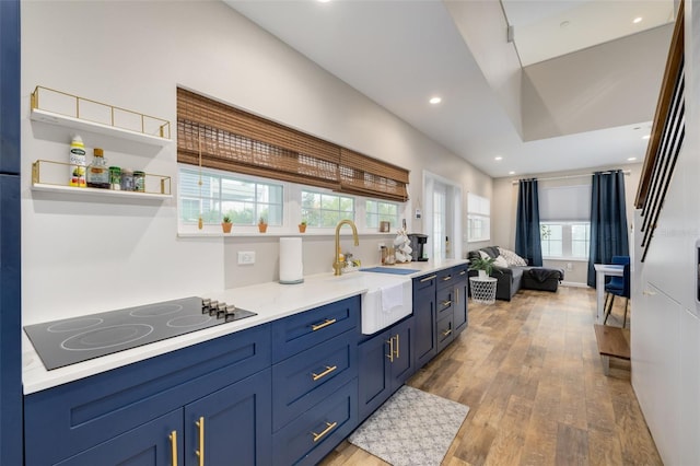 719 Douglas Ave, Dunedin, FL 34698 - kitchen with black electric stovetop, light wood-type flooring, blue cabinetry, light countertops, and open floor plan