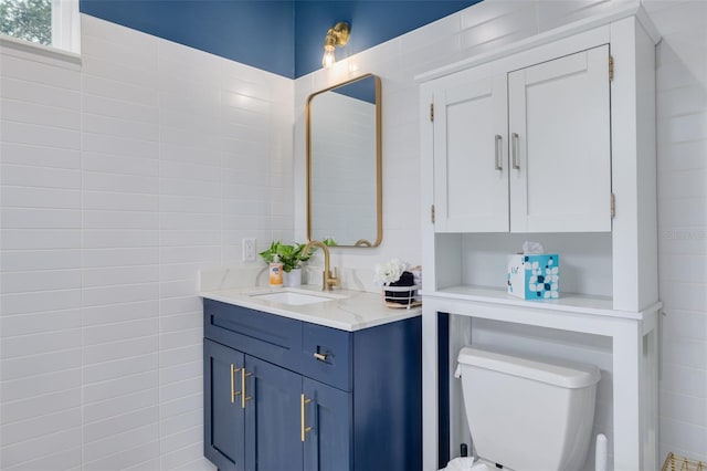 bathroom with vanity, tile walls, and toilet