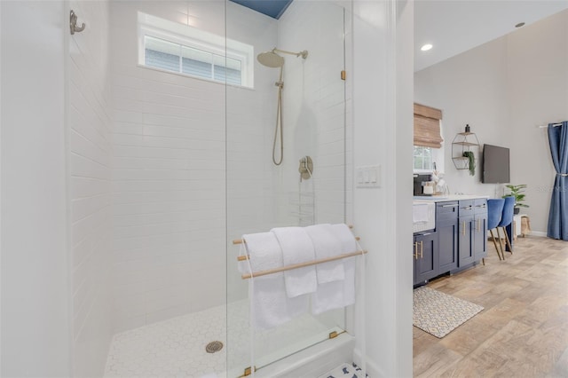 bathroom with a tile shower, hardwood / wood-style flooring, and a wealth of natural light