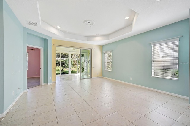 tiled spare room with a tray ceiling