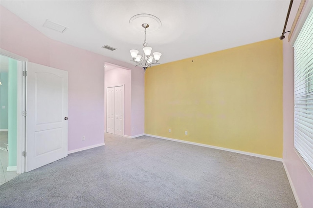 carpeted empty room featuring a chandelier