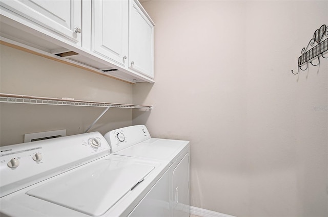 clothes washing area with cabinets and washing machine and clothes dryer