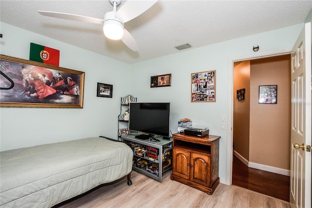 bedroom with light wood-type flooring, a textured ceiling, and ceiling fan