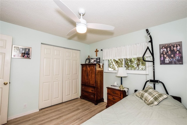 bedroom featuring light hardwood / wood-style floors, a textured ceiling, ceiling fan, and a closet