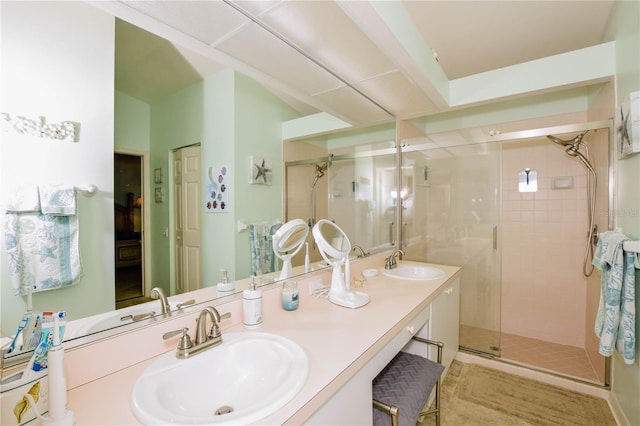 full bathroom with double vanity, a stall shower, and a sink