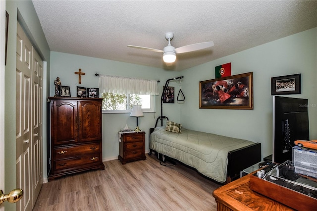 bedroom with light wood-style flooring, a textured ceiling, a ceiling fan, and a closet