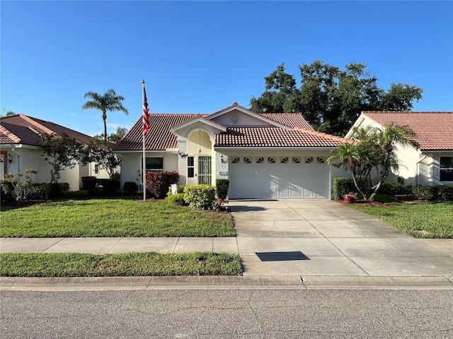mediterranean / spanish home featuring a tiled roof, an attached garage, stucco siding, driveway, and a front lawn