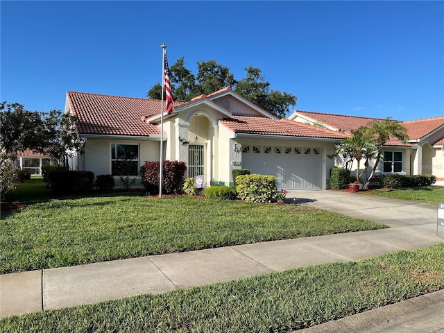 mediterranean / spanish-style home featuring a tiled roof, stucco siding, an attached garage, and a front lawn