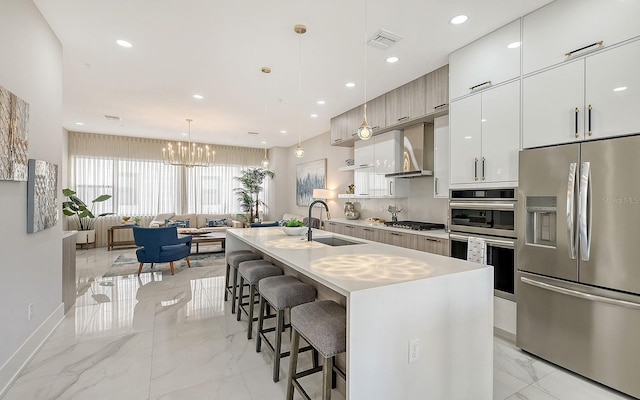 kitchen featuring appliances with stainless steel finishes, sink, pendant lighting, a breakfast bar area, and an island with sink