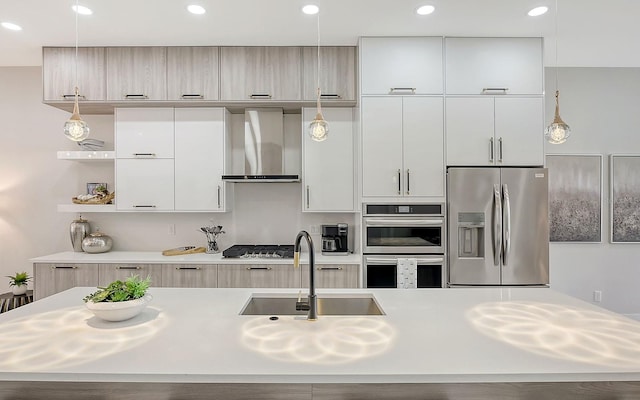 kitchen featuring pendant lighting, wall chimney range hood, sink, and appliances with stainless steel finishes