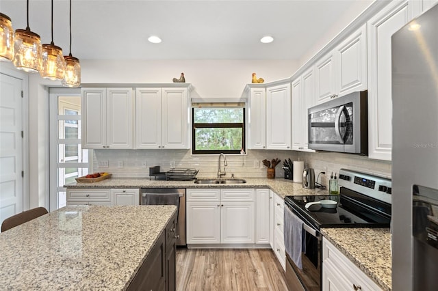 kitchen with white cabinets, sink, decorative backsplash, light hardwood / wood-style floors, and stainless steel appliances