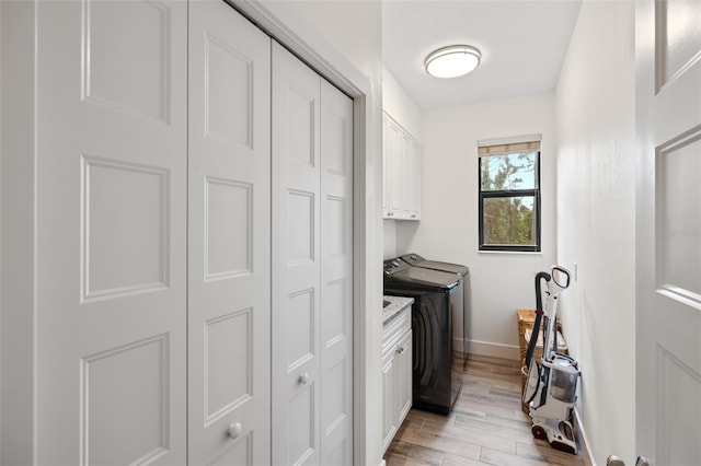 laundry room with light hardwood / wood-style floors, cabinets, and washing machine and clothes dryer