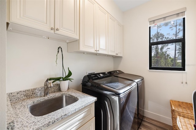 laundry area with cabinets, sink, hardwood / wood-style flooring, and washing machine and clothes dryer