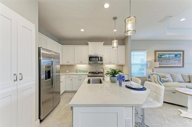 kitchen featuring stainless steel appliances, white cabinetry, sink, and pendant lighting