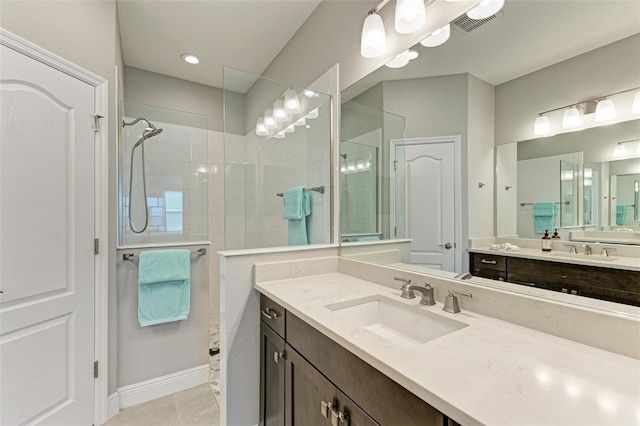 bathroom with vanity, tile patterned flooring, and a tile shower