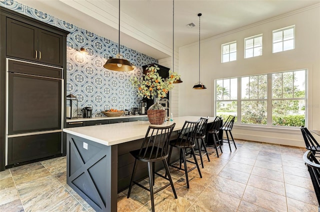 kitchen featuring pendant lighting, ornamental molding, a kitchen breakfast bar, and a kitchen island