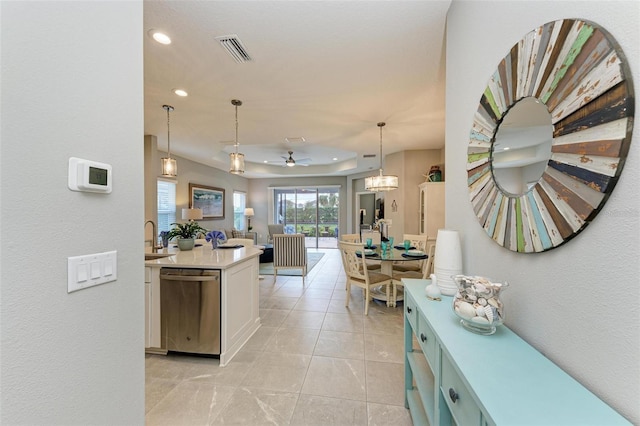 kitchen featuring sink, decorative light fixtures, stainless steel dishwasher, a tray ceiling, and white cabinets