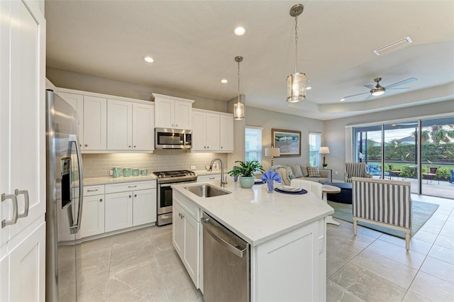 kitchen with white cabinetry, stainless steel appliances, a kitchen island with sink, and sink