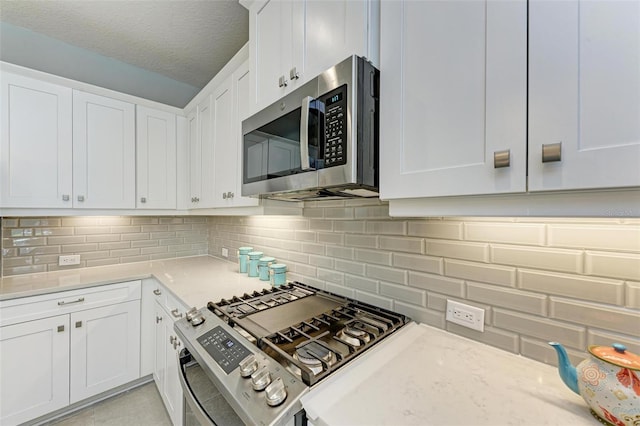 kitchen featuring stainless steel appliances, tasteful backsplash, white cabinets, and a textured ceiling