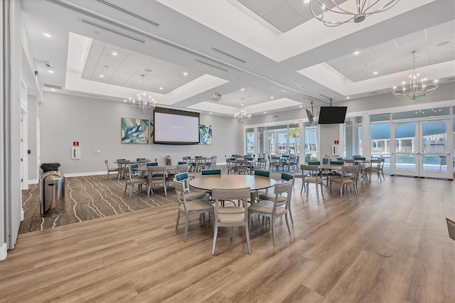 dining area with light hardwood / wood-style floors, a raised ceiling, and plenty of natural light