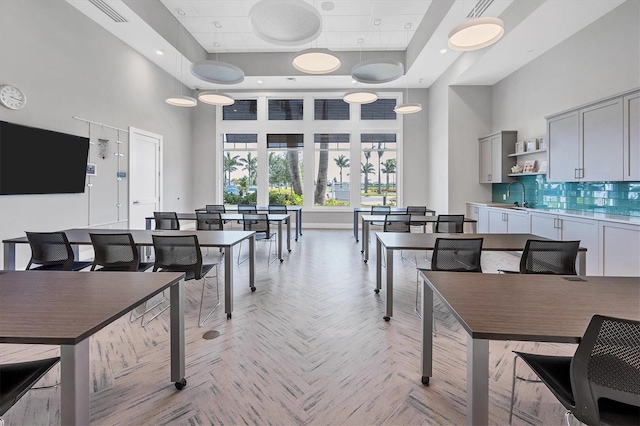 dining area with a high ceiling, a tray ceiling, light parquet floors, and sink