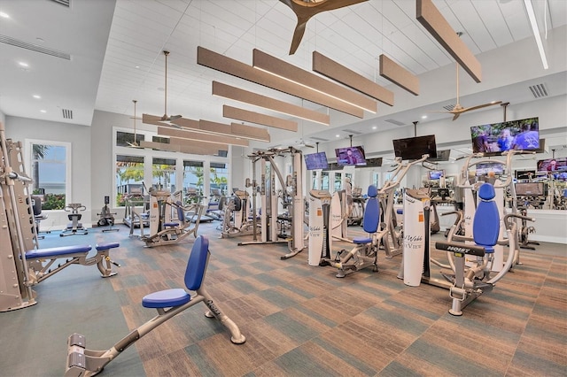 workout area with carpet, a wealth of natural light, a towering ceiling, and ceiling fan