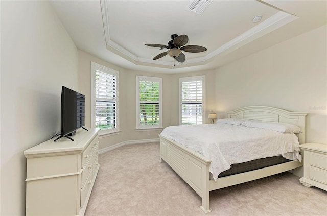 bedroom featuring ceiling fan, light colored carpet, crown molding, and a tray ceiling